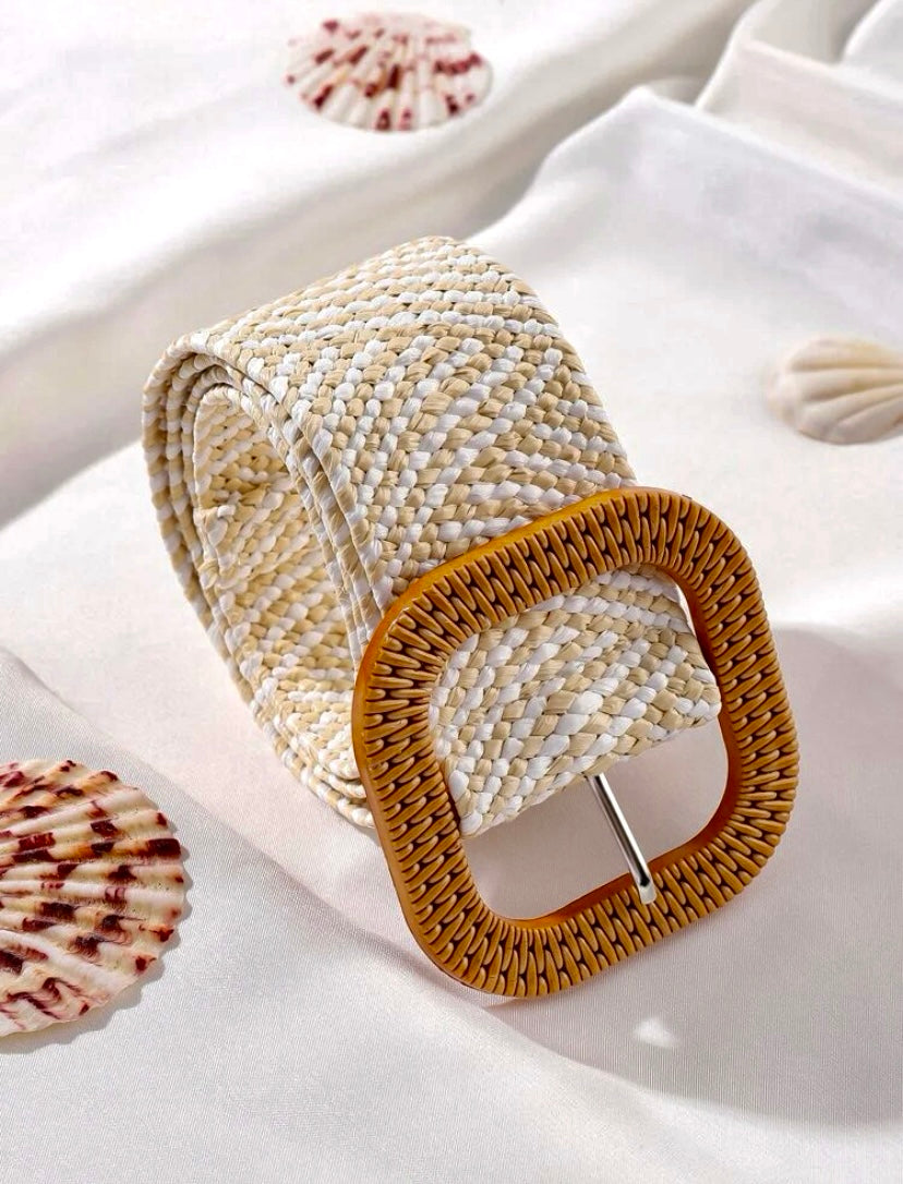 Beige white elasticated belt with a woven texture and a rectangular rattan buckle, displayed on fabric with seashell accents.